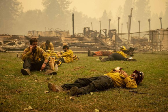 September 10, 2020, Berry Creek, California, USA: A Cal Fire crew takes a break in the grass next to Berry Creek Elementary School, which was destroyed overnight during the Bear Fire. The crews only g ...