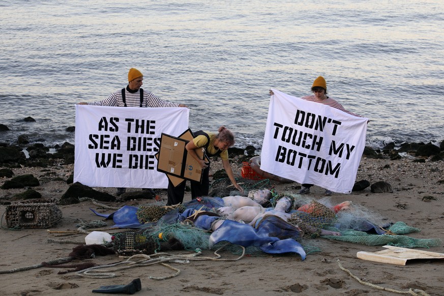 27.06.2022, Portugal, Lissabon: Aktivisten der Ocean Rebellion veranstalten am Ufer des Tejo eine Performance, bei der sie ein Ende aller nationalen Treibstoffsubventionen f