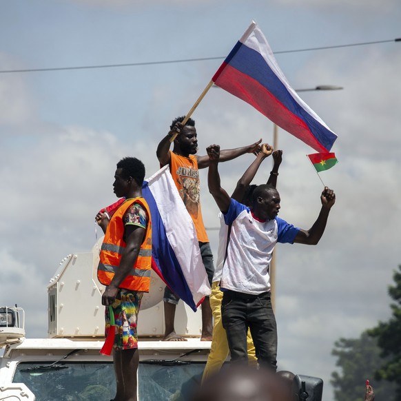 FILE - Supporters of Capt. Ibrahim Traore wave Russian flags as they cheered in the streets of Ouagadougou, Burkina Faso, Oct. 2, 2022. Questions are swirling in Burkina Faso about what role Russia ma ...