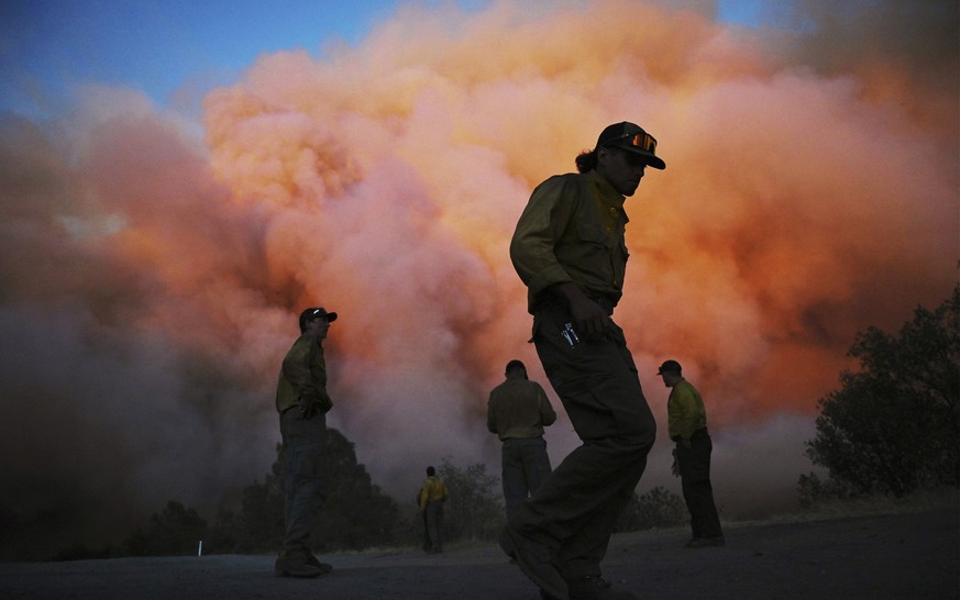 U.S. Forest firefighters stand along Triangle Road watching a wildfire called the Oak Fire burn east of Midpines in Mariposa County, Calif., Friday, July 22, 2022. The fast-moving wildfire near Yosemi ...