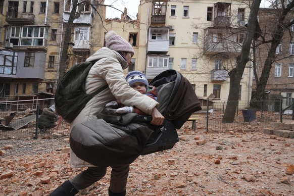 ARCHIV - 30.01.2023, Ukraine, Charkiw: Eine Frau trägt ihr Kind, während sie aus einem Wohnhaus im Stadtzentrum evakuiert wird, das von einer russischen Rakete getroffen wurde. Wie die ukrainischen Be ...