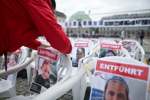 ARCHIV - 04.10.2024, Berlin: Eine Frau befestigt während der Installation «Platz der Hamas-Geiseln» des Bündnis Freiheit für die Hamas-Geiseln auf dem Bebelplatz ein Bild von Ariel Bibas, der mit sein ...