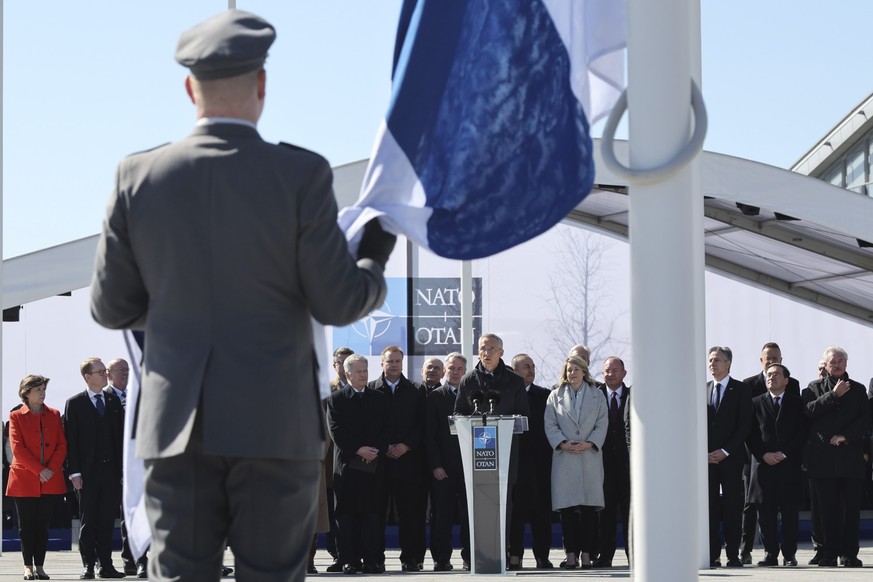 04.04.2023, Belgien, Brüssel: Jens Stoltenberg (M), Nato-Generalsekretär, spricht während Militärpersonal die Flagge Finnlands vor dem Nato-Hauptquartier hisst. Finnland ist der 31. Mitgliedsstaat der ...