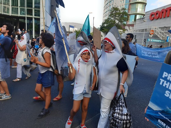 Eine Familie läuft die Demonstration als Haie verkleidet mit. 
