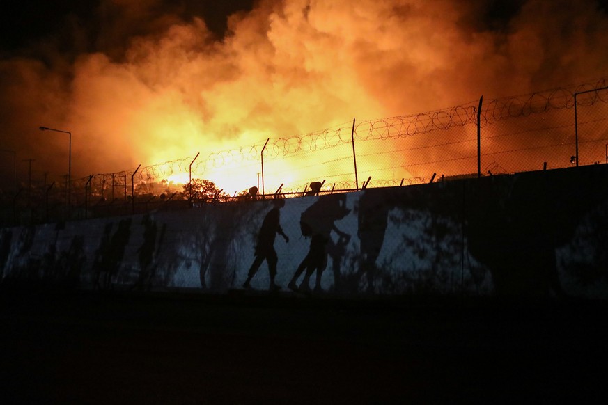 Refugees and migrants carrying their belongings are silhouetted as they flee from a fire burning at the Moria camp on the island of Lesbos, Greece, September 9, 2020. REUTERS/Elias Marcou