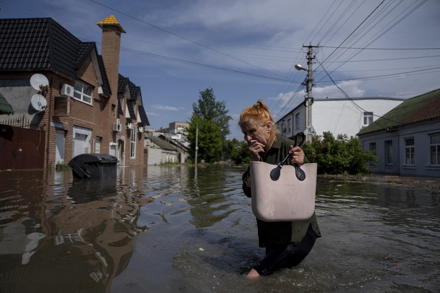 A local resident makes her way through a flooded road after the walls of the Kakhovka dam collapsed overnight, in Kherson, Ukraine, Tuesday, Jun 6, 2023. Ukraine on Tuesday accused Russian forces of b ...