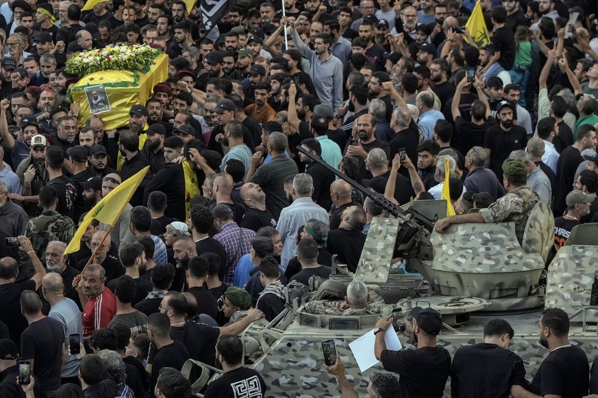 Lebanese army soldiers sit on their armoured vehicle as mourners carry the coffin of Mohammed Mahdi, son of Hezbollah legislator Ali Ammar, who was killed Tuesday after his handheld pager exploded, in ...