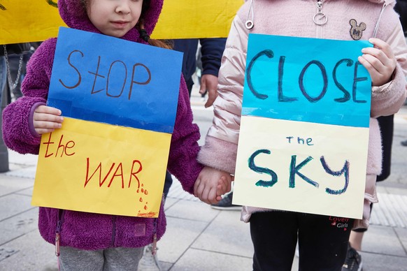 Zwei ukrainische Kinder mit Schildern auf denen sie Fordern, den Luftraum über der Ukraine zu schützen.