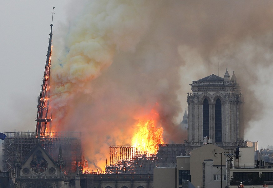 Flames rise from Notre Dame cathedral as it burns in Paris, Monday, April 15, 2019. Massive plumes of yellow brown smoke is filling the air above Notre Dame Cathedral and ash is falling on tourists an ...