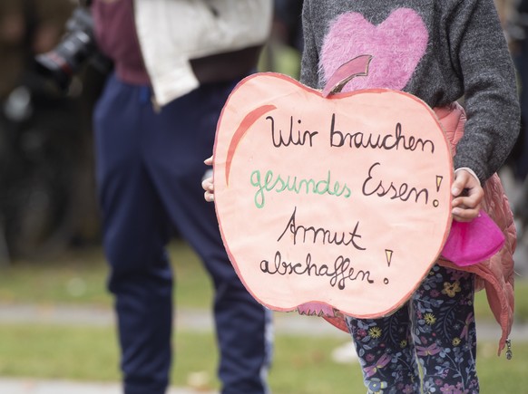 15.10.2022, Berlin: Ein Kind hält bei der Kundgebung der Initiative #ichbinarmutsbetroffen am Bundeskanzleramt ein Plakat mit der Aufschrift «Wir brauchen gesundes Essen! Armut abschaffen!». #IchBinAr ...