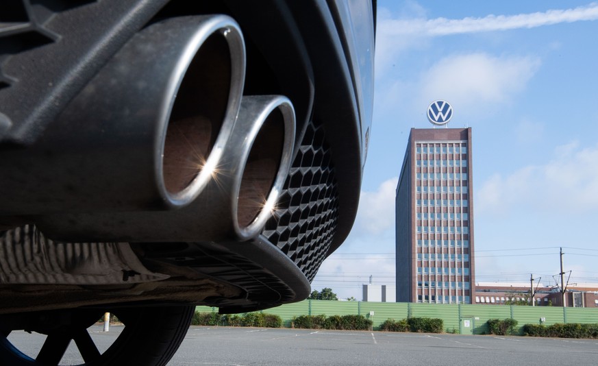 ARCHIV - 11.08.2021, Niedersachsen, Wolfsburg: Auspuffrohre eines Volkswagen, fotografiert mit dem Markenhochhaus am VW Werk Wolfsburg. (zu dpa