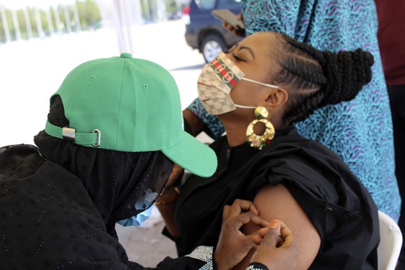 A woman receives an AstraZeneca coronavirus vaccine in Abuja, Nigeria Friday, Nov 19, 2021. Nigeria on Friday launched a mass rollout of COVID-19 vaccines as it aims to protect its population of more  ...