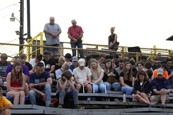 People bow their heads during a vigil for Corey Comperatore, the former fire chief shot and killed at a weekend rally for former President Donald Trump, Wednesday, July 17, 2024, at Lernerville Speedw ...