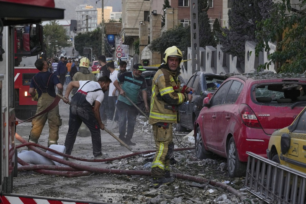 dpatopbilder - 13.06.2025, Iran, Teheran: Feuerwehrleute und Menschen säubern den Schauplatz einer Explosion in einer Wohnanlage nach einem israelischen Angriff auf die iranische Hauptstadt Teheran. F ...
