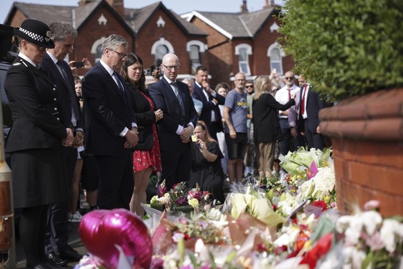 British Prime Minister Keir Starmer, third from left, observes floral tributes near the scene in Hart Street, where three children died and eight were injured in a knife attack during a Taylor Swift e ...