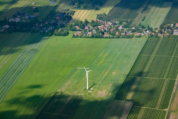 Ein Windrad steht auf einem Feld nahe einer kleinen Ortschaft.