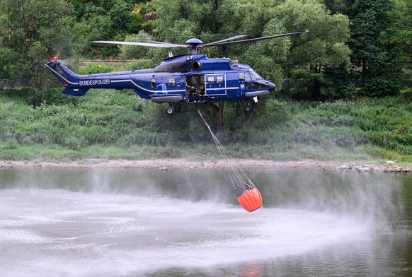 27.07.2022, Sachsen, Schmilka: Ein Hubschrauber der Bundespolizei nimmt mit einem L�schwasser-Au�enlastbeh�lter aus der Elbe Wasser auf um einen Brand im Nationalpark S�chsische Schweiz zu l�schen. Fo ...