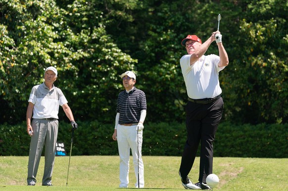 President Donald J. Trump, joined by Japan Prime Minister Shinzo Abe and Hall of Fame professional golfer Isao Aoki, watches his tee shot during their golf game on May 26, 2019, at the Mobara Country  ...