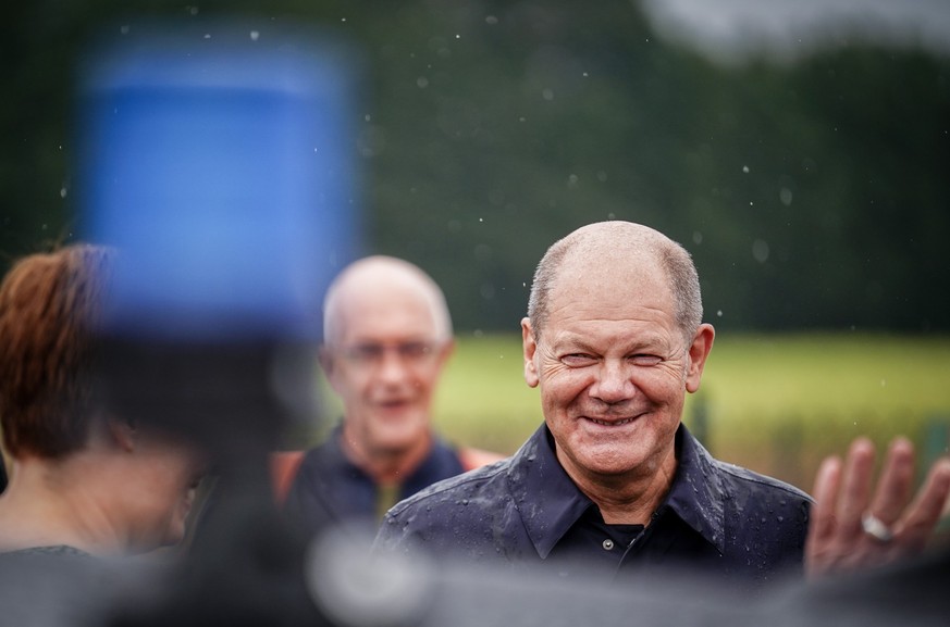 20.08.2022, Brandenburg, Trebbin/Ot Klein Schulzendorf: Der Bundeskanzler und SPD-Bundestagsabgeordnete Olaf Scholz verabschiedet sich nach seinem Besuch der Agrargenossenschaft AGT Trebbin im Regen.  ...