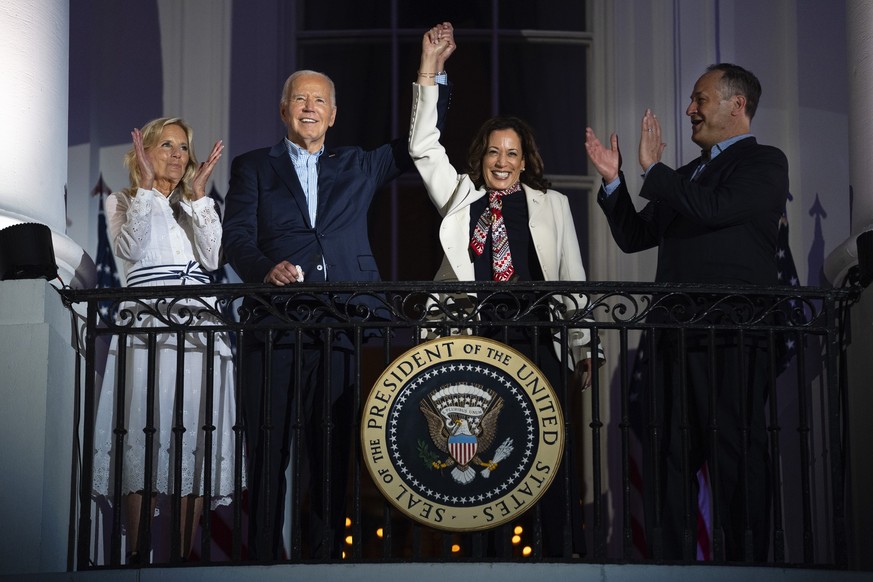 First lady Jill Biden, left, and second gentleman Douglass Emhoff, right, watch as President Joe Biden, center left, raises the hand of Vice President Kamala Harris as they view the Independence Day f ...