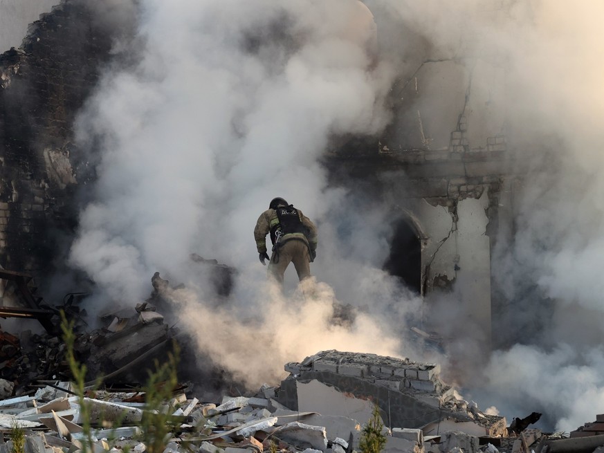 ARCHIV - 10.05.2024, Ukraine, Charkow: Ein Feuerwehrmann geht durch den Qualm eines brennenden Hauses, nach russischen Beschuss. Die russische Armee scheint die von den ukrainischen Verteidigern erwar ...