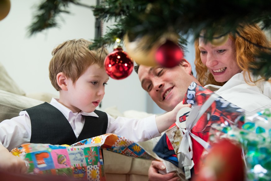 ILLUSTRATION - Eine Familie sitzt am 05.12.2017 in einer Wohnung in Hamburg unter dem Weihnachtsbaum und oeffnet die Geschenke (gestellte Szene). Foto: Christin Klose | Verwendung weltweit