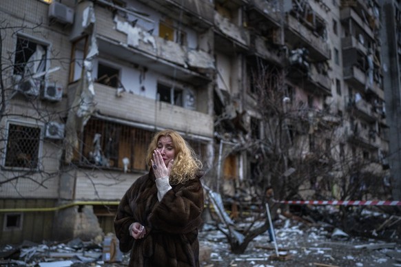 Eine Ukrainerin vor einem durch einen Raketenangriff zerstörten Haus.