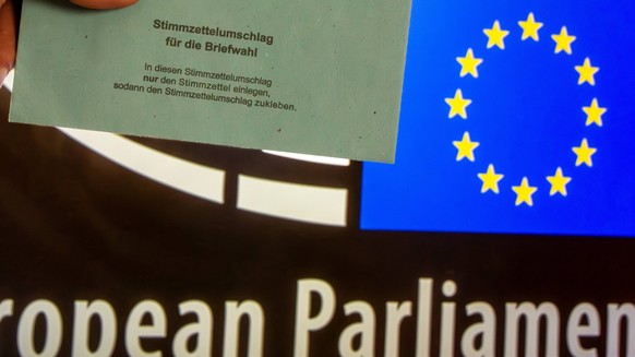 Symbolbild Europawahl: Umschlag zur Briefwahl vor dem Schriftzug und Wappen des EU-Parlamentes. Die n