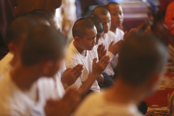 Members of Wild Boars soccer team listen to a monk pray after a ceremony marking the completion of their serving as novice Buddhist monks following their dramatic rescue from a cave in Mae Sai distric ...