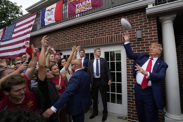 dpatopbilder - 09.09.2023, USA, Ames: Donald Trump (r), ehemaliger Präsident der USA, wirft einen Football in die Menge während eines Besuchs der Alpha Gamma Rho, einer Studentenverbindung, an der Iow ...