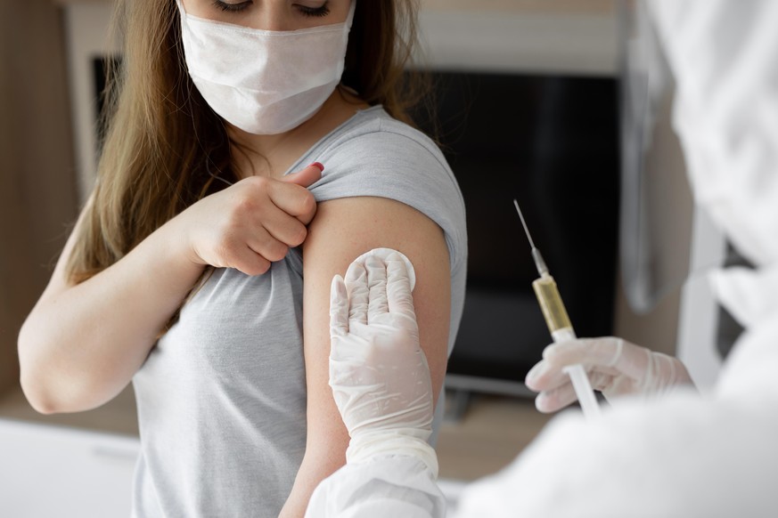 Doctor in personal protective suit or PPE inject vaccine shot to stimulating immunity of woman patient at risk of coronavirus infection. Coronavirus,covid-19 and vaccination concept.