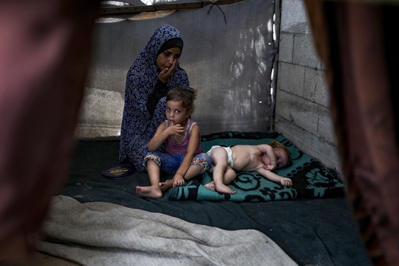 Palestinian Manar al-Hessi, who was displaced by the Israeli bombardment of the Gaza Strip, sits next to her children, at a makeshift tent camp in Deir al-Balah, central Gaza Strip, Monday, July 29, 2 ...