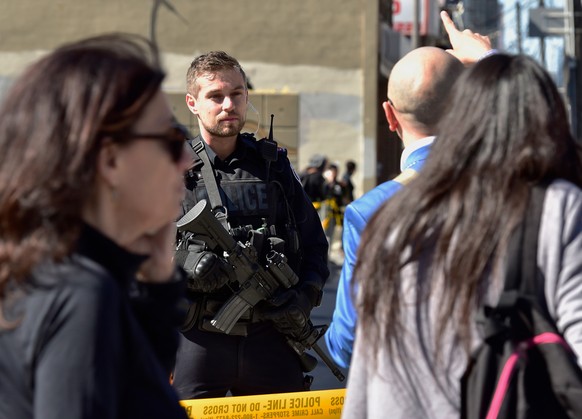 A Toronto police officer stands guard at the police line after a van mounted a sidewalk crashing into pedestrians in Toronto on Monday, April 23, 2018. The van apparently jumped a curb Monday in a bus ...