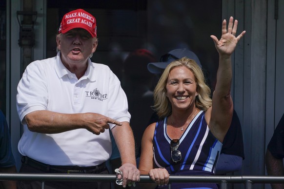 FILE - Rep. Marjorie Taylor Greene, R-Ga., waves while former President Donald Trump points to her while they look over the 16th tee during the second round of the Bedminster Invitational LIV Golf tou ...