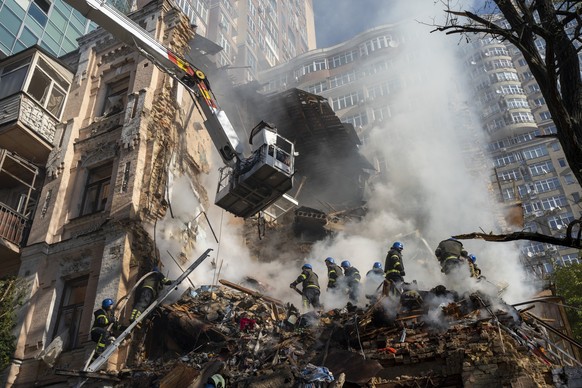 17.10.2022, Ukraine, Kiew: Feuerwehrleute arbeiten nach dem Beschuss auf Geb�ude durch eine Drohne. Russland hat am Montagmorgen Kiew erneut mit Drohnen angegriffen. Laute Explosionen ersch�tterten di ...