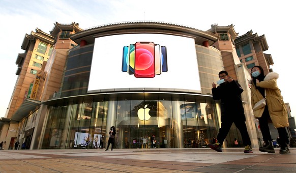 Chinese walk past an Apple showroom in a popular, international shopping mall in Beijing on Wednesday, January 27, 2021. Apple reported strong demand for the iPhone 12 in China, closing out 2020, with ...