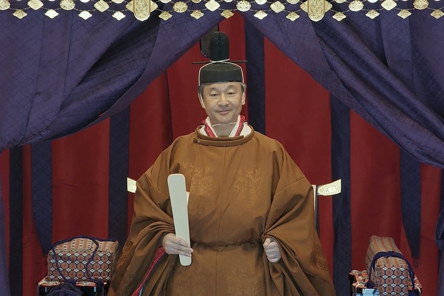 In this image made from video, Japan's Emperor Naruhito stands on the Imperial Throne as Naruhito proclaims his ascension to the Chrysanthemum Throne at the Imperial Palace in Tokyo, Tuesday, Oct. 22, ...