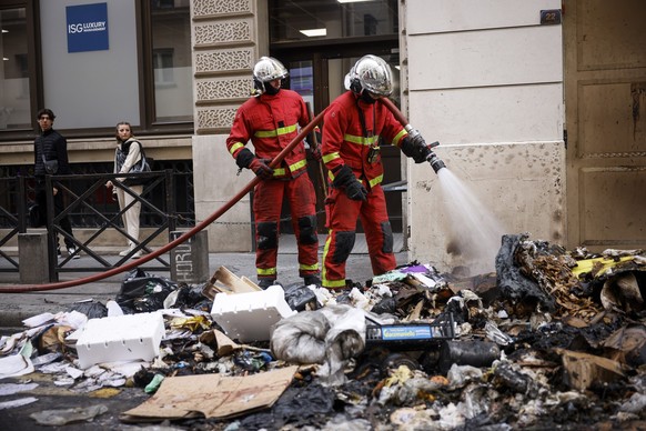 Firemen controlling the remains of a garbage fire from last night protests against the retirement bill in Paris, Friday, March 24, 2023. French President Macron's office says state visit by Brita ...