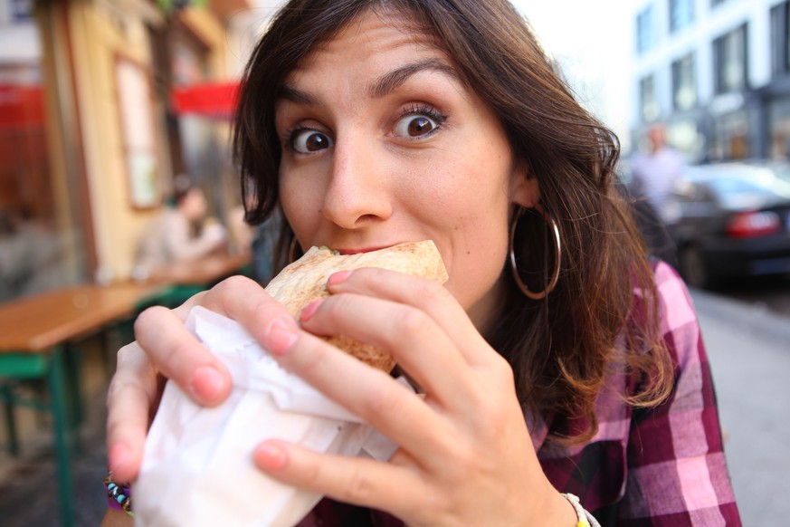 Young Woman eating the typical Berliner doner kebab, sitting in any restaurant at the street