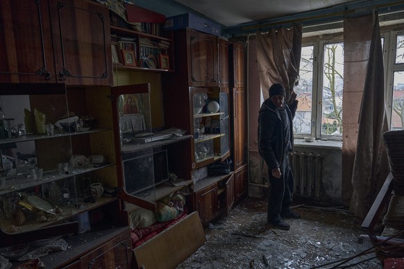 05.02.2023, Ukraine, Cherson: Ein Mann betrachtet die Glasscherben auf dem Boden seiner Wohnung nach einem russischen Beschuss. Foto: -/LIBKOS/AP/dpa +++ dpa-Bildfunk +++