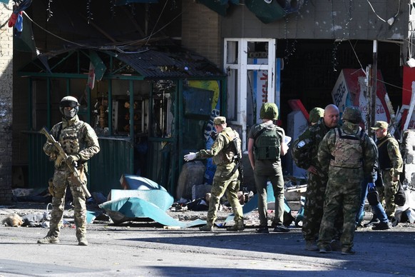 Russische Soldaten untersuchen eine zerstörte Tankstelle in Donezk.