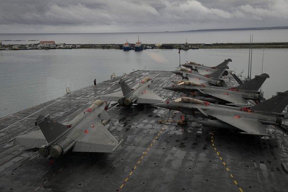 A French crew member runs near to the Rafale jet fighters on France's nuclear-powered aircraft carrier Charles de Gaulle, at Limassol port, Cyprus, Tuesday, March 1, 2022. France's nuclear-powered air ...