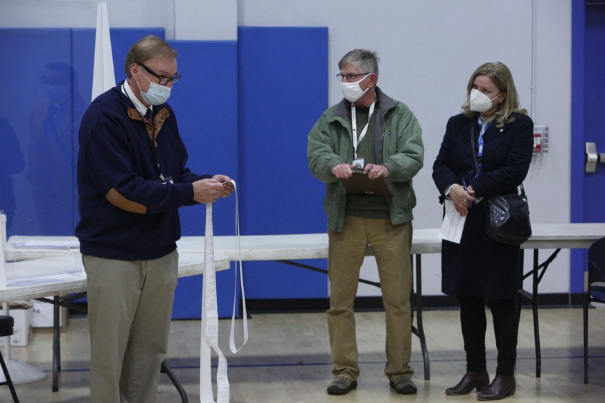 Wahlbeobachter schauen dem Leiter (Moderator) eines Wahllokals in der US-amerikanischen Stadt Concord dabei zu, wie er am am Tag der US-Präsidentschaftswahl die Wählerstimmen überprüft, die vom optischen Scan-Wahlgerät ausgedruckt wurden.