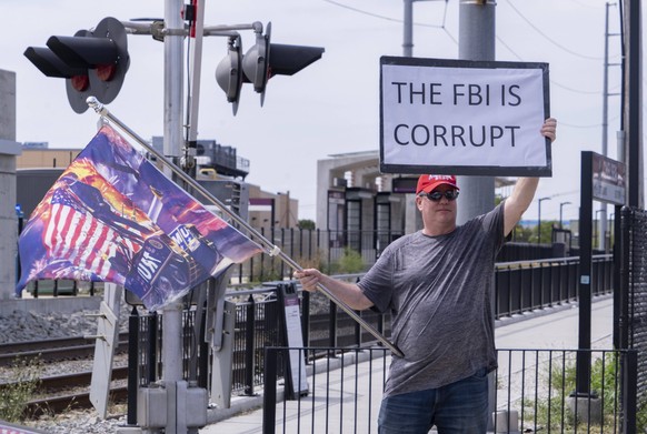 August 21, 2022, FBI s Boston Division offices, Chelsea, Massachusetts, U.S: A demonstrator holds a sign and Trump flag during a rally against the FBI, outside of the FBI s Boston Division offices in  ...