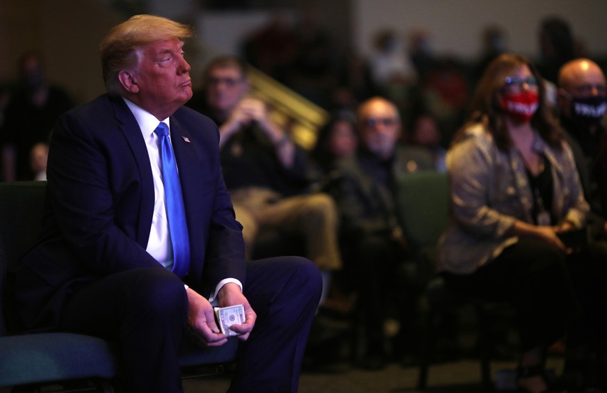 U.S. President Donald Trump holds money before donating it as he attends a mass at the International Church of Las Vegas Service in Las Vegas, Nevada, U.S., October 18, 2020. REUTERS/Carlos Barria