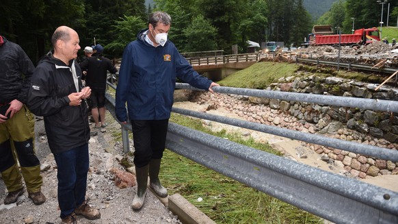 Markus Söder, Vorsitzender der CSU und bayerischer Ministerpräsident, und Olaf Scholz (SPD,M), Bundesfinanzminister und Kanzlerkandidat, stehen bei der durch Unwetter zerstörten Bob- und Rodelbahn am ...
