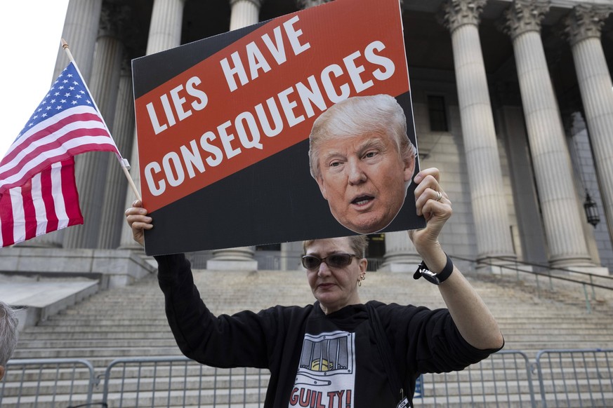 USA, Proteste gegen Donald Trump vor dem Supreme Court in New York September 22, 2023, New York, New York, USA: A person holds an American flag and a sign with an image of TrumpÃââ s face that reads Ã ...