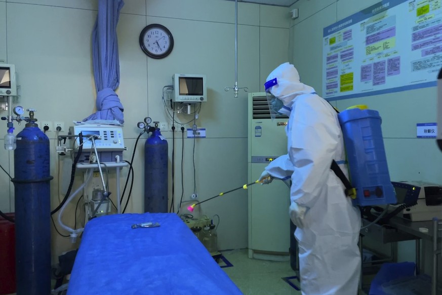 23.12.2022, China, Baigou: Ein Krankenhausmitarbeiter in Schutzkleidung desinfiziert die Station einer Notaufnahme des Baigou New Area Aerospace Hospital. China hat mit einer massiven Corona-Welle zu  ...