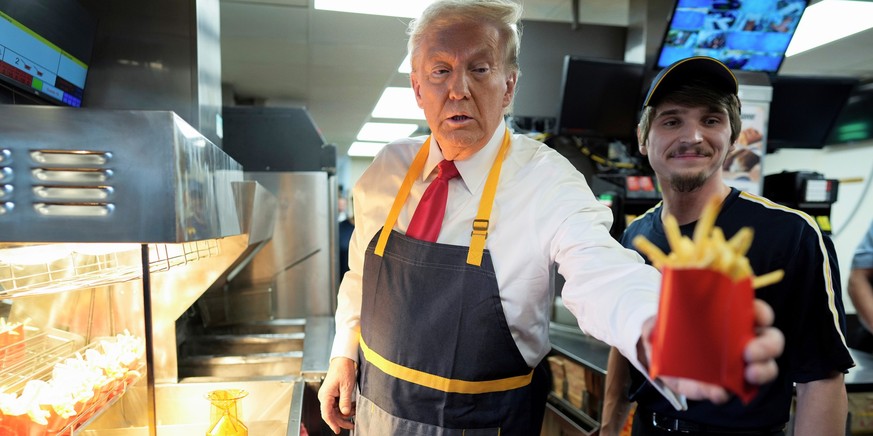 dpatopbilder - 20.10.2024, USA, Philadelphia: Donald Trump (l), US-Präsidentschaftskandidat der Republikaner und ehemaliger US-Präsident, gibt eine Pommes-Bestellung aus, nachdem er mit einem Angestel ...