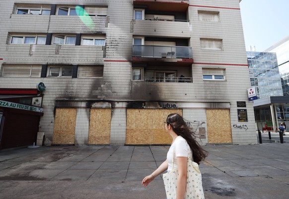 230701 -- NANTERREFRANCE, July 1, 2023 -- A woman walks past a burnt bank in Nanterre, western Paris suburbs, France, June 30, 2023. Violence continued in France overnight from Thursday to Friday afte ...